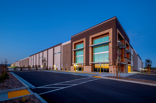 Large warehouse exterior, dusk.