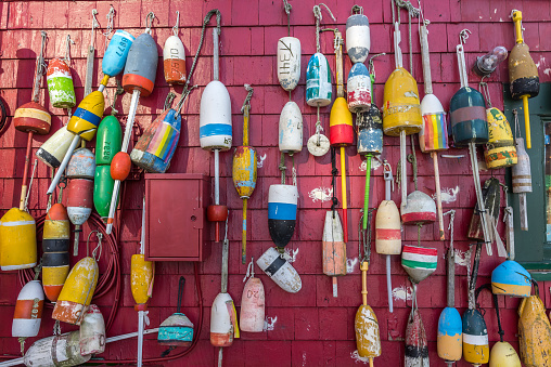 Colorful traditional lobster buoys hanging on the outside wall of a fishing shack in Boston. Each lobsterman paints his own design in his own color scheme on his buoys in order to mark his trap territory.