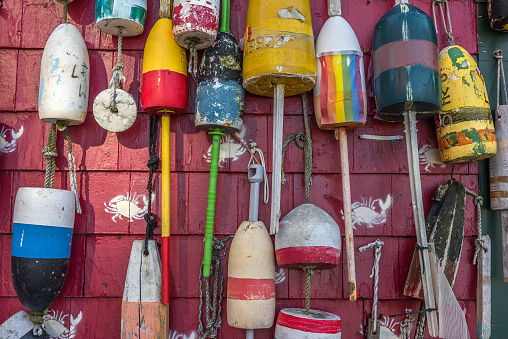 Colorful traditional lobster buoys hanging on the outside wall of a fishing shack in Boston. Each lobsterman paints his own design in his own color scheme on his buoys in order to mark his trap territory.