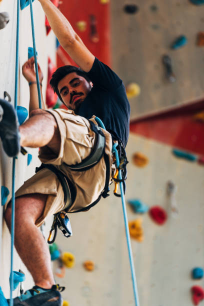 istock Young man climbing artificial rock wall at gym 1361821353