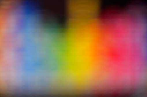 Defocused abstract multi colored background against black background.