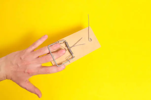 Man hand was caught in a mousetrap on a yellow background.Concept, risks, and failures