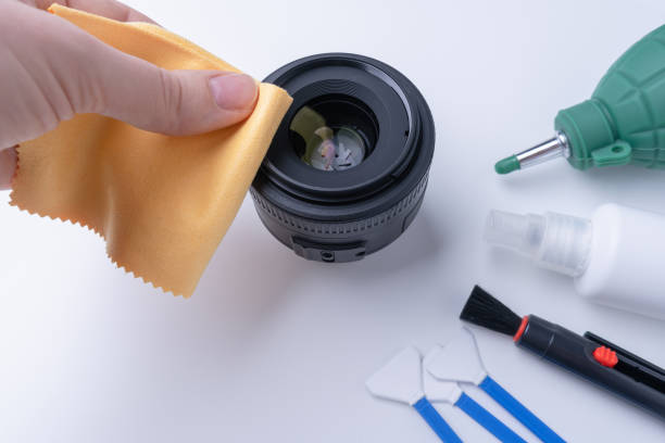 istock Photographer's hand with yellow microfiber wipes the camera lens 1361842853