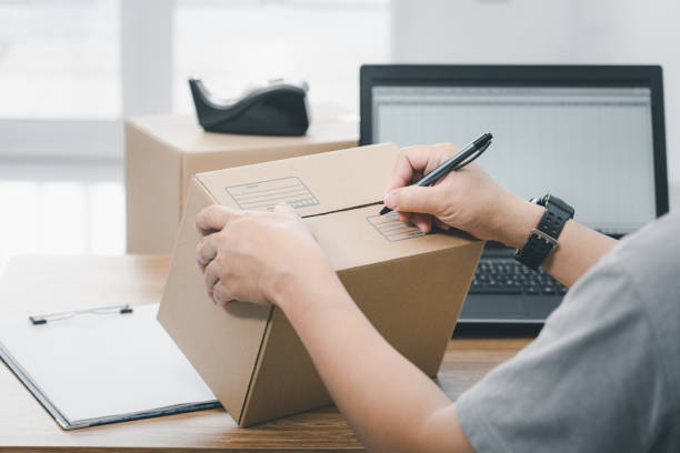 istock Close up hand a man use pen write on parcel box about the parcel delivery address and use laptop to register in the online system 1361842940