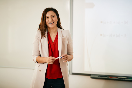 Portrait of happy professor teaching in the classroom and looking at camera.