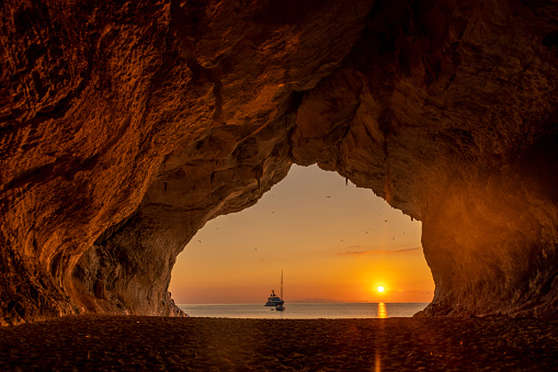 Cueva de Cala Luna al atardecer con veleros de fondo, Cerdeña, Italia. photo