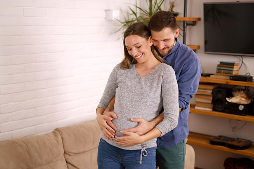 Happy husband caresses the belly of his pregnant woman