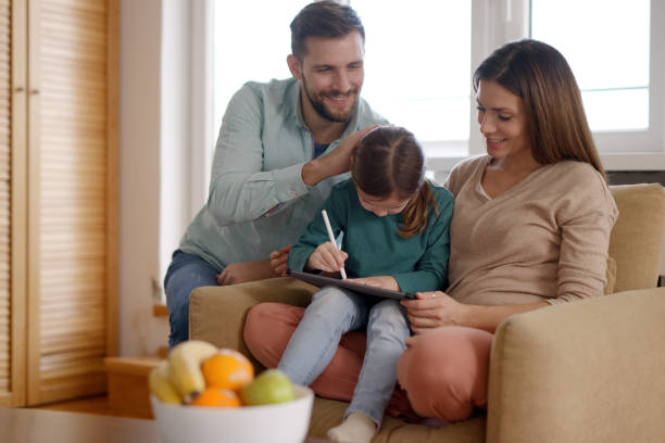 istock Happy parents and their daughter using digital tablet at home 1361848982