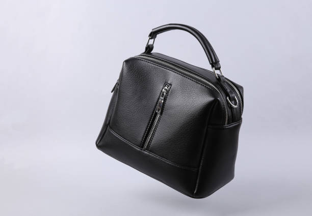 Classic black leather bag levitating on gray background stock photo