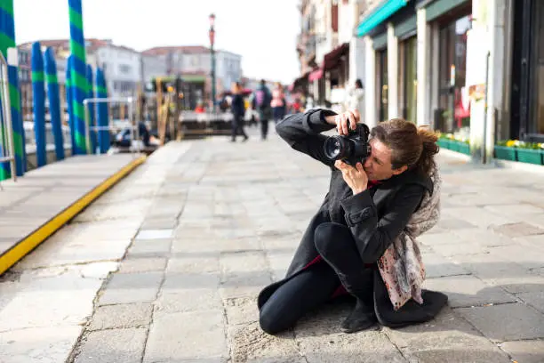 Photo of Mid adult woman tourist in Venice taking photographs