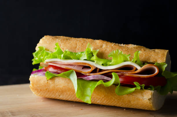 istock Fresh submarine sandwich with ham, cheese, bacon, tomatoes, lettuce and onions 1361861901