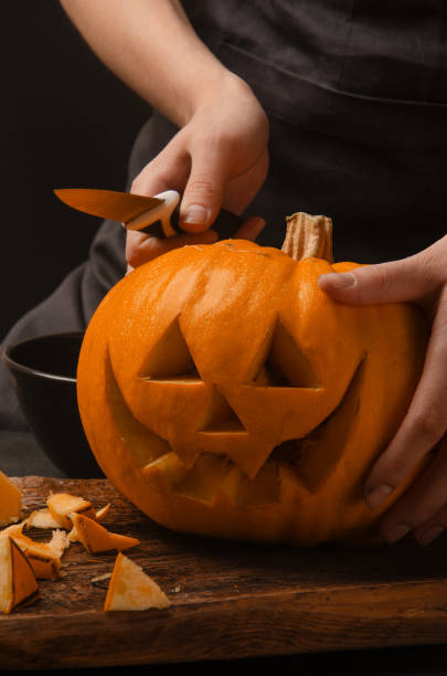 istock Hands cutting, carving pumpkin into jack-o-lanterns for halloween 1361862538