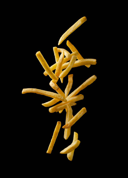 French fries - fried potatoes flying. French fries - fried potatoes flying. Fly fastfood isolated on black background. french fries stock pictures, royalty-free photos & images