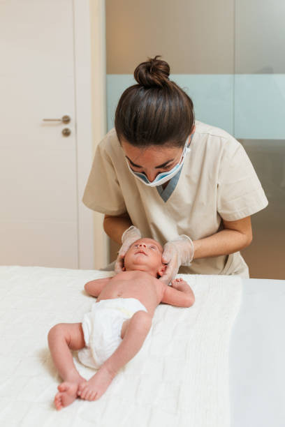 Female physiotherapist doing a positional plagiocephaly correction on a newborn baby in a therapy center. Female physiotherapist doing a positional plagiocephaly correction on a newborn baby in a therapy center. Medical and health concept. plagiocephaly stock pictures, royalty-free photos & images