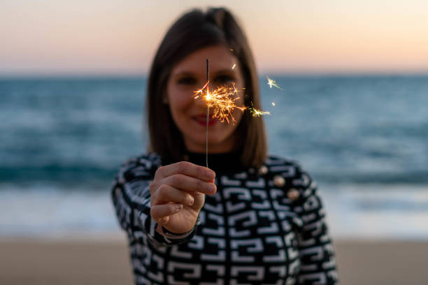 istock Young woman making a wish with her magic sparkler in the sand 1361867247