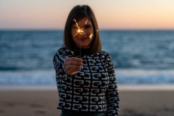 istock Young woman making a wish with her magic sparkler in the sand 1361867263