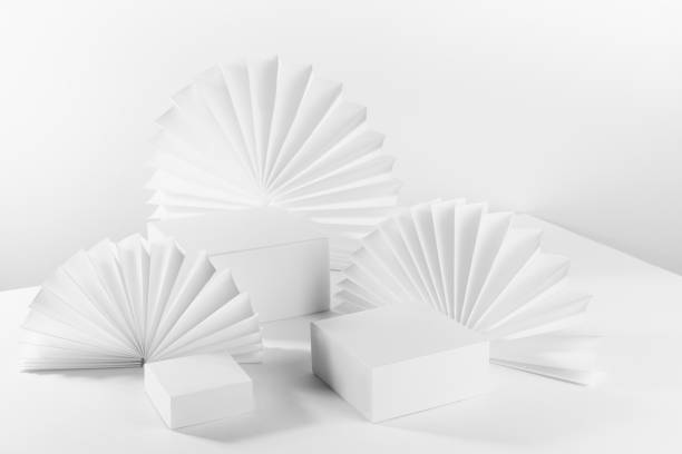 istock White light abstract scene with three different square podiums on table mockup as showcase for displaying, presentation cosmetic product, goods with asian ribbed paper fans, side view, corner, 3d. 1361867482