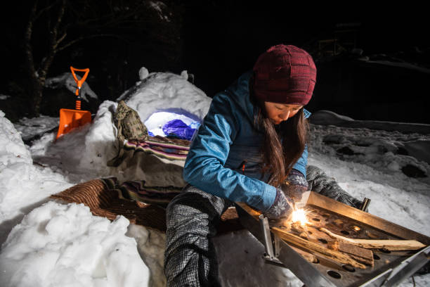 istock A woman starting campfire with ferro rod at snow camp 1361870096