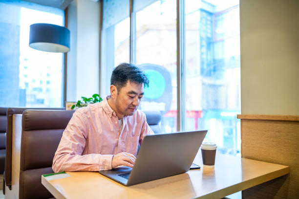istock Asian middle-aged man using laptop in coffee shop 1361875964