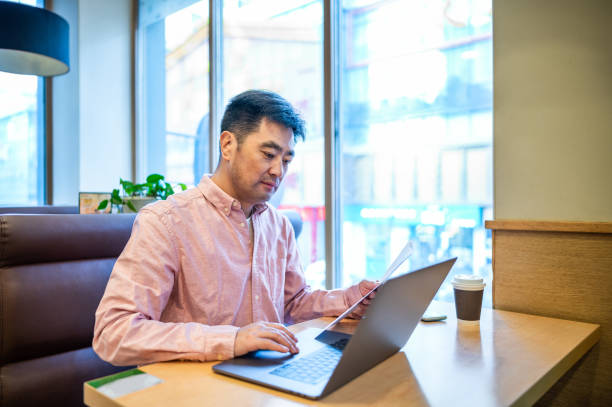 istock Asian middle-aged man using laptop in coffee shop 1361875978