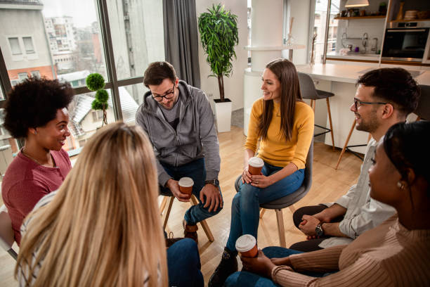 istock Diverse group of people sitting in circle in group therapy session. 1361876040