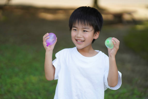 istock Boy playing with water balloons 1361876109