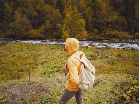 Man hikes mountains with travel backpack. Wandering lifestyle, adventure concept autumn vacation outdoors, alone in wild. Travel to North Caucasus, Arkhyz, Russia