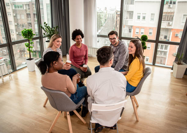 istock Diverse group of people sitting in circle in group therapy session. 1361876445