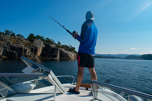 Male Fisherman with fishing rod on a boat in the ocean near Stavanger Norway (jig fishing)