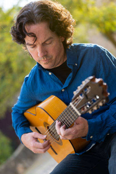 istock Middle-aged man playing Spanish guitar sitting on park bench 1361884292