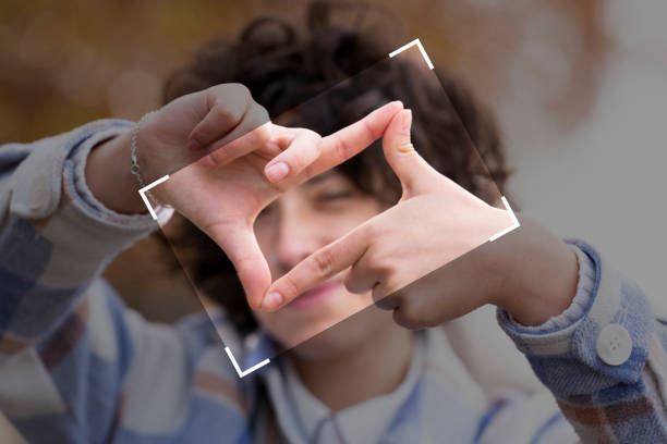 young brunette woman with curly hair making the framing sign with her hands - imagination creativity finger frame frame imagens e fotografias de stock