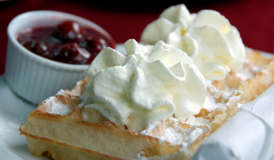 Belgian waffle with whipped cream ,powdered sugar and cherry.