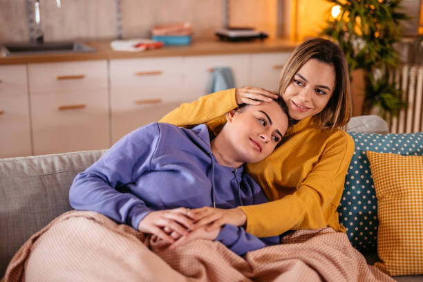 istock Young lesbian couple sitting under blanket together and embracing 1361890171