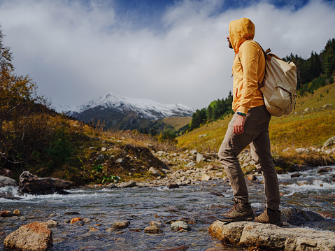 Man hikes mountains with travel backpack. Wandering lifestyle, adventure concept autumn vacation outdoors, alone in wild. Travel to North Caucasus, Arkhyz, Russia