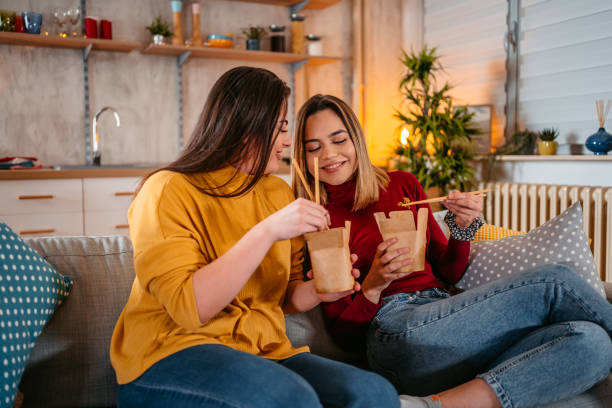 Lesbian couple relaxing at home and eating pasta