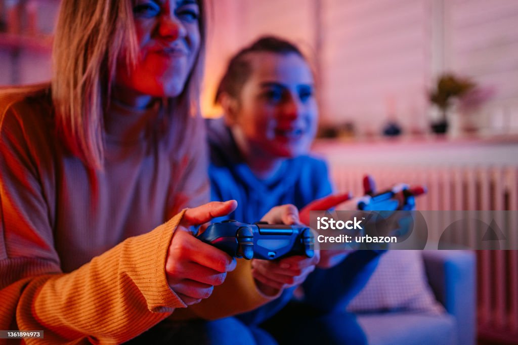 Lesbian couple playing videogames together Young beautiful homosexual couple of lesbian woman sitting on couch in living room at home enjoy and excited holding console playing game together. LGBT family pride concept. Control Stock Photo