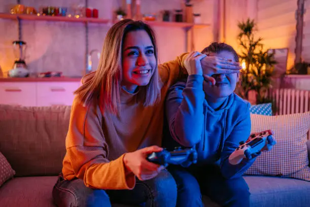 Young beautiful homosexual couple of lesbian woman sitting on couch in living room at home enjoy and excited holding console playing game together. LGBT family pride concept.