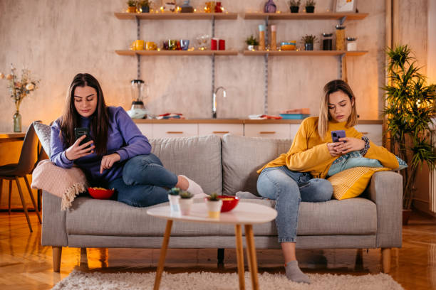 istock Lesbian couple ignoring each other using phone after an arguing 1361895266