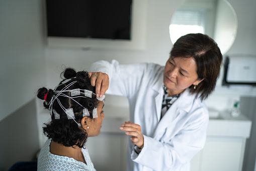 Doctor placing electrodes on patient's head for a medical exam