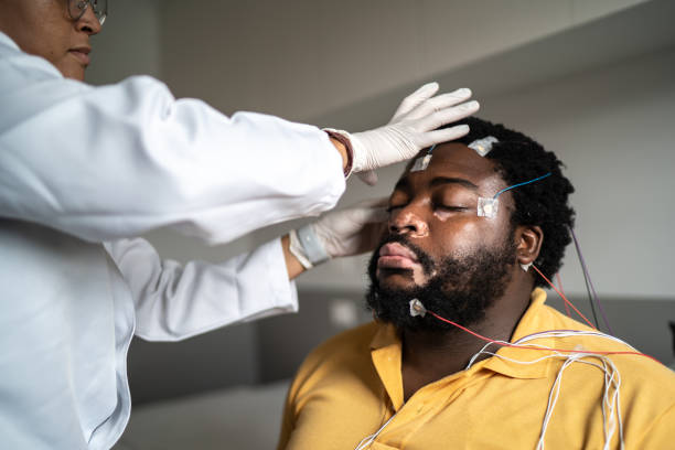 istock Doctor placing electrodes on patient's head for a polysomnography (sleep study) 1361896711