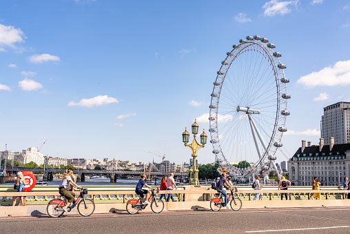London, UK - Cyclists and pedestrians on Westminster Bridge crossing the Thames in central London, with the London Eye on the horizon.