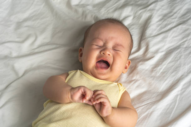 Asian baby crying out loud on the bed stock photo