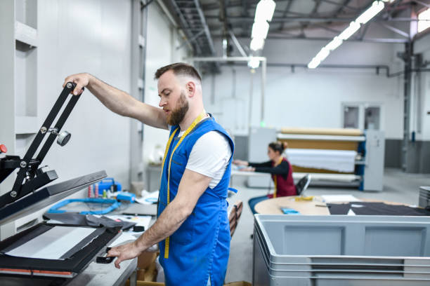 istock Bearded Textile Worker Using Press Machine For Design Printing On Cloth In Factory 1361897608