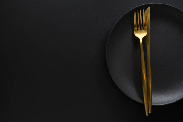 juego de cubiertos dorados con plato oscuro - silverware fork place setting napkin fotografías e imágenes de stock