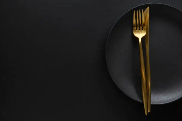 Photo of Golden cutlery set with dark plate