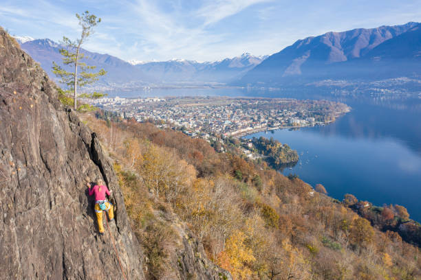 若い女性のロッククライマーは、急な登山、壮大な山の湖の景色につながります - conquering adversity endurance adventure danger ストックフォトと画像