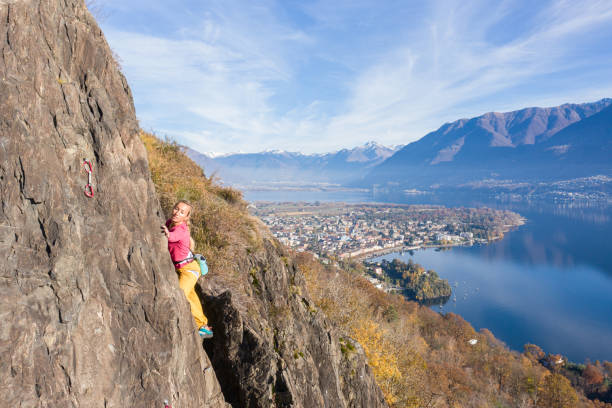 若い女性のロッククライマーは、急な登山、壮大な山の湖の景色につながります - conquering adversity endurance adventure danger ストックフォトと画像