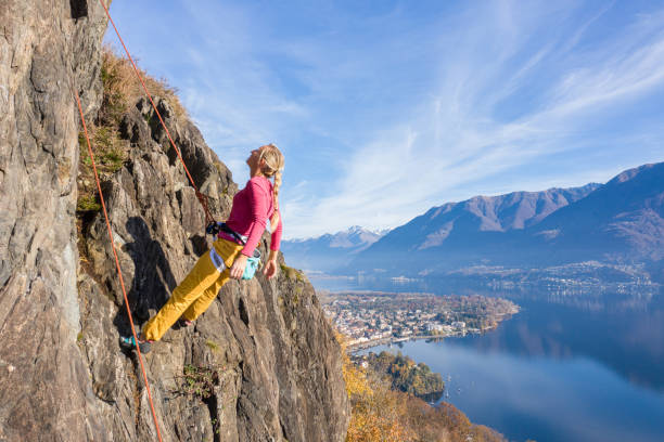 若い女性のロッククライマーは、急な登山、壮大な山の湖の景色につながります - conquering adversity endurance adventure danger ストックフォトと画像