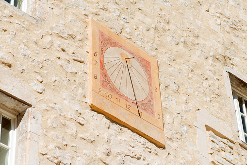 antique medieval engraved sundial on a stonewall facade
