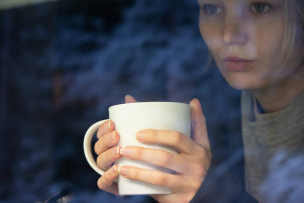 des femmes solitaires et tristes tenant une tasse et rêvant pour l’avenir, regardant par la fenêtre - beautiful boredom sensuality desire photos et images de collection